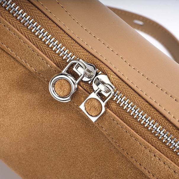 Close-up of a brown textured zipper on a bag with a white background.