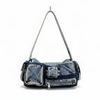 Denim handbag on a white surface with a striped garment in the background