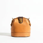 Person holding a brown leather handbag with a blurred indoor background