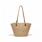 Woven beige handbag with brown straps on a hanger against a clothing store background.
